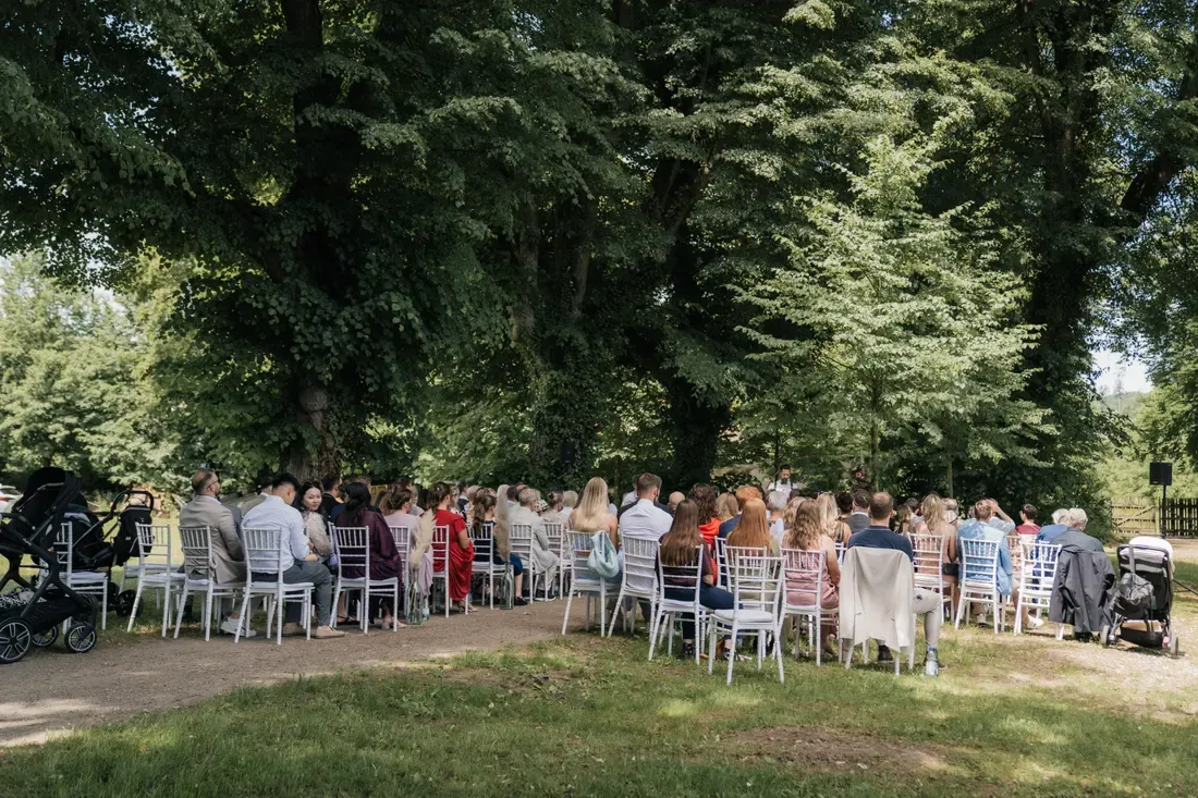 Hochzeitsgäste sitzen im Park von Schloss Beuggen bei der freien Trauung