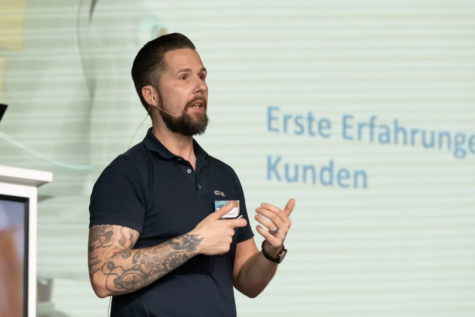 Moderator Stefan Kramberg spricht mit Headset auf der Bühne eines Firmenevents